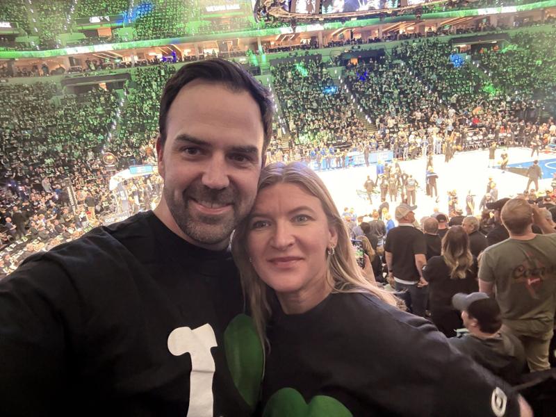 Greg and Natasha at a basketball game in a packed arena