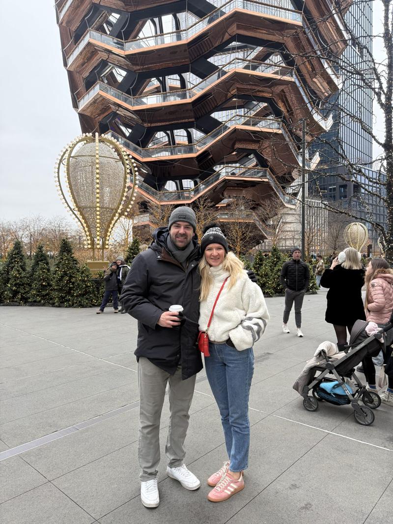 Greg and Natasha in winter coats in front of a spiral landmark staircase